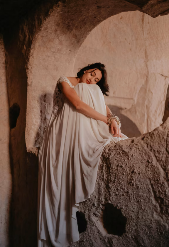 Person in a white dress in a natural stone arch